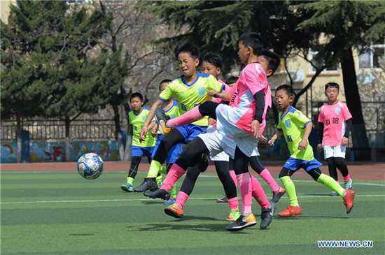 Pupils take part in football training in elementary school in Qingdao